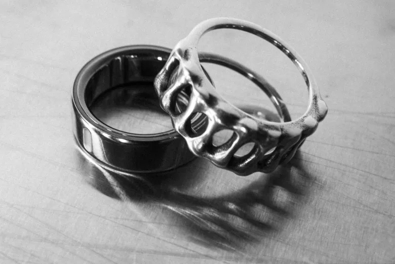 金属の台の上に、スマートリングとシルバーのリングジャケットが並んでいるモノクロ写真